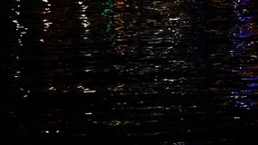 Streaks of lights on rippling sea water surface at night time. Dark background. Real time full hd video footage.