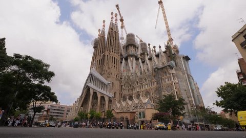 BARCELONA, SPAIN - AUGUST 12, 2018: Famous Barcelona landmark, Sagrada la Familia, still under construction as for August 2018, full height establishing shot. Tourists around building, tower cranes