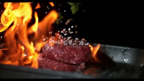 Super slowmotion footage of throwing fresh beef meat burger and herbs on ignited pan, 1000fps 4k