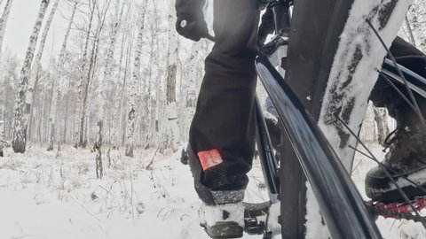 Action cam on frame installed behind. Close-up pov view. Professional extreme sportsman biker riding fat bike in outdoors. Cyclist ride in winter snow forest. Man does trick on mountain bicycle.