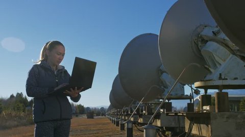 Woman student operator of institute of Solar Terrestrial Physics monitors communication equipment in notebook. Unique array solar radio telescope. 