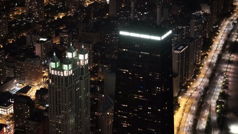 Chicago, Illinois - Circa-2015: Aerial view orbiting the John Hancock Center at night, featuring Lake Michigan and Chicago's cityscape
