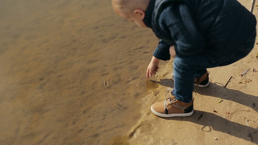 Little boy playing near the lake. Slow motion