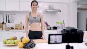 Blogger sporty Asian woman using camera recording how to make apple juice video for her subscriber