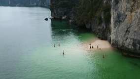 People are swimming on a hidden beach in Ha long Bay, Vietnam. Drone video.
