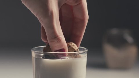 Female hand Dipping a chocolate chip cookie in milk. Slow Motion
