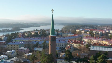 Aerial footage of the Stora Essingen church tower with a golden christian cross on top in Stockholm, Sweden