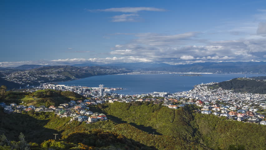 Beautiful day in Wellington, New Zealand. Timelapse video of the cityscape with ferries and boats moving in the bay and scattered clouds flying over the city.