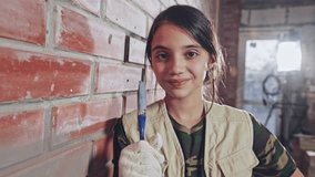 Teenage girl holding up paintbrush and smiling