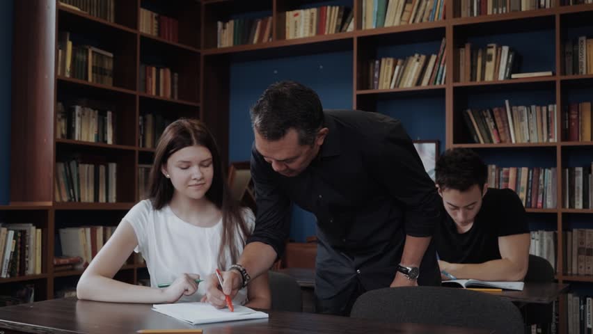 Student getting help from tutor in library at the university Royalty-Free Stock Footage #1020018472
