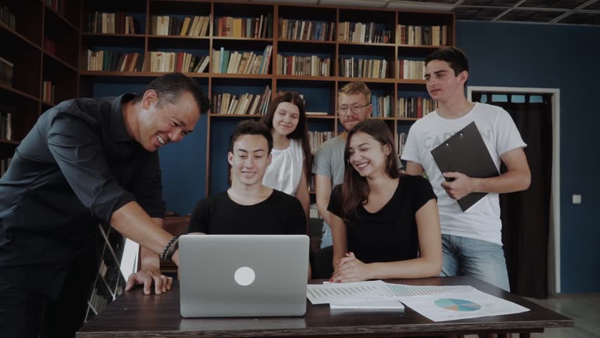 Group of international students working on a project with the teacher. International young smily students at the meeting with mentor. Royalty-Free Stock Footage #1020018481