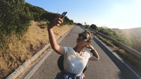 Happy young woman taking selfie pictures with smartphone riding scooter motorbike on Ponza island at sunset. Couple shooting selfie video in front of the sea. 27_Ponza_Collinetta_GOPRO_07