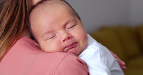 Loving Mother Cuddling Sleeping Newborn Baby Son Over Shoulder