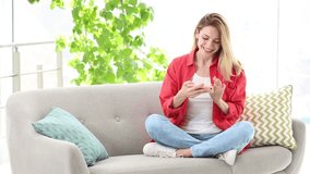 Young woman taking selfie while sitting on sofa at home
