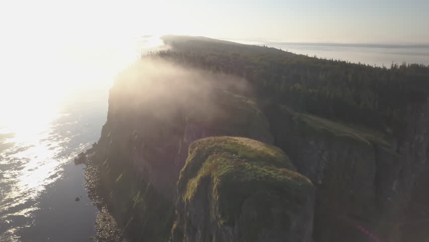 Sunrise over the foggy, rocky cliffs and tidal waters of Cape Split, Nova Scotia.