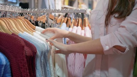 女性の手の接写は 服屋で服を選ぶハンガーを引いた ブルネットの女性の手が 買い物街で服を買う服のラックを横切る 販売促進とショッピングのコンセプト の動画素材 ロイヤリティフリー Shutterstock