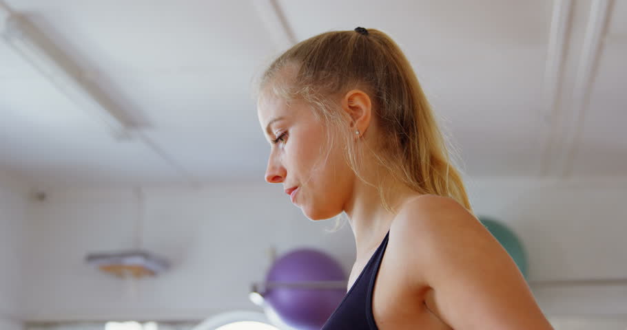 Side view close up of Caucasian female boxer exercising with skipping rope in fitness studio 4k