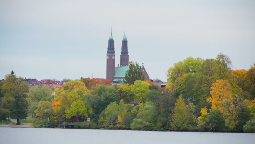 A church on the back of the trees in Stockholm Sweden as seen while cruising along the river inside the boat