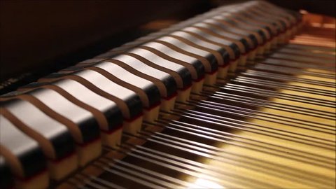 Inside of a grand piano, hammers moving while pianist plays Bach