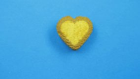 Female hand paints heart-shaped cookies on a blue background with a brown tube icing funny faces
