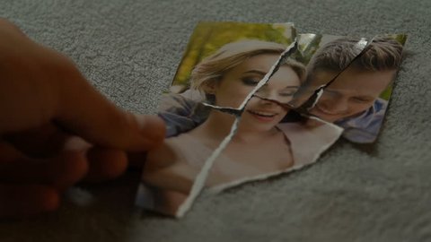Male hands connecting tearing pieces of photo with his girlfriend, yearning