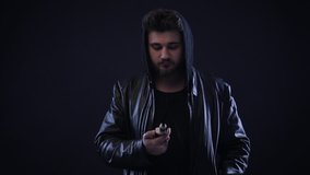 Man smoking electronic cigarette, vape in dark clothes. vapor on black background. Slow motion video