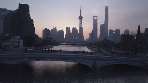 Shanghai China Circa-2017, daytime low sweeping view of the cityscape, gliding over water.