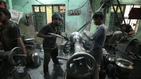 DHAKA, BANGLADESH - NOVEMBER 26, 2018: Hard working kids doing child labor in a small sweatshop where they produce aluminium under dangerous and difficult circumstances