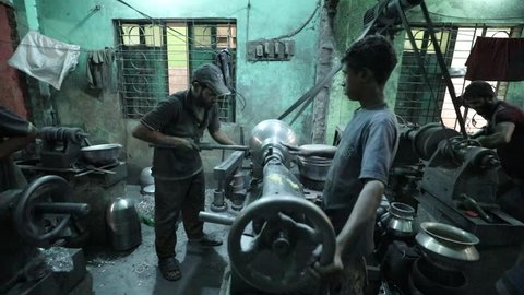 DHAKA, BANGLADESH - NOVEMBER 26, 2018: Hard working kids doing child labor in a small sweatshop where they produce aluminium under dangerous and difficult circumstances