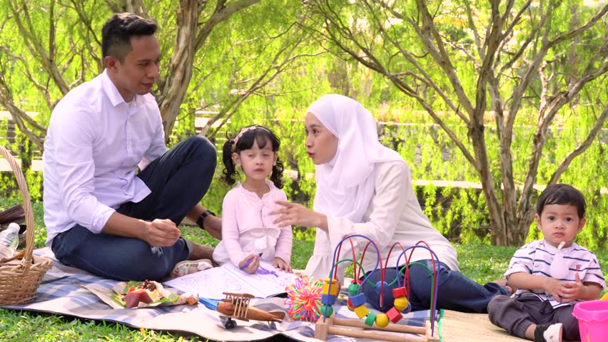 Happy and lovely family spending their quality time at green park, picnic and learning together.  Royalty-Free Stock Footage #1020064783