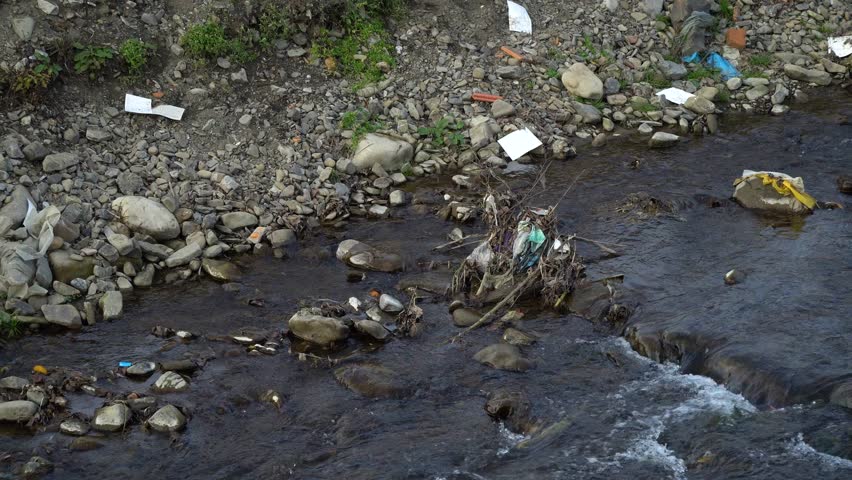 Rubbish on the river. Garbage in a mountain river. Environmental pollution. Pollution of nature. Ecological catastrophy. Non-degradable plastic. | Shutterstock HD Video #1020066682