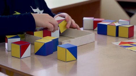 Children's hands are engaged in creativity. Colored cubes