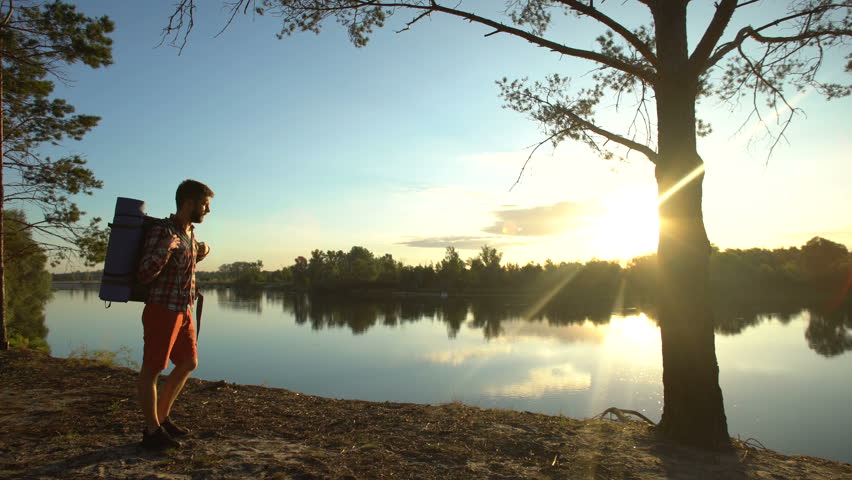 Camper taking off backpack near forest river, enjoying amazing landscape, hike