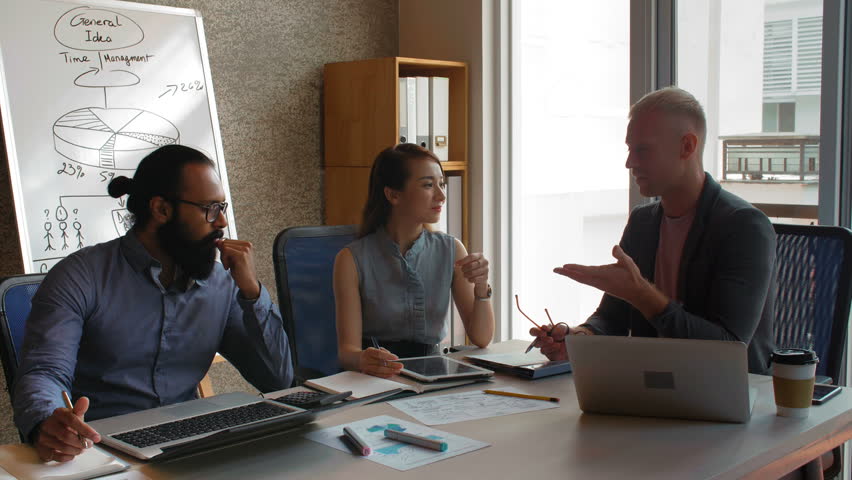 Multiethnic group of business people sitting in conference room, discussing effective company strategies and sharing creative ideas 
