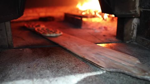 Traditional Turkish Pita or pide bread with sesame on wooden oar in brick oven or stone stove oven. Bakery or bakehouse concept image. Turkish cuisine ramadan iftar product.