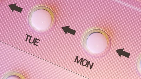 Pink birth control pills in a feminine blister. Single pill for every day of a week. Modern female contraception medicine. Top view camera moving sideways in an endless, seamless, looping animation.
