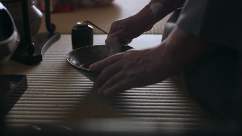 Tea master using a bamboo matcha tea whisk to whisk the powder with hot water in a bowl in a traditional Japanese home with soft day lighting. Close up shot on 4k RED camera.
