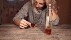 woman sitting at the table at home and drinking whiskey. the concept of female alcoholism