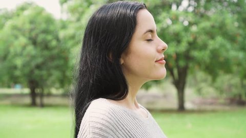 Side view portrait of a young woman breathing fresh air relaxing in the park
