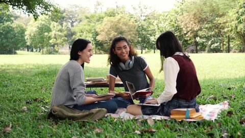 Group of three diversity university student friends smiling and laughing in the park
