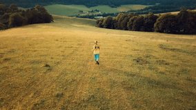 Aerial View Running woman. Runner is jogging in summer sunny day around trees and mountains background under sun light with blue sky, Drone 4K Video Aerial View
