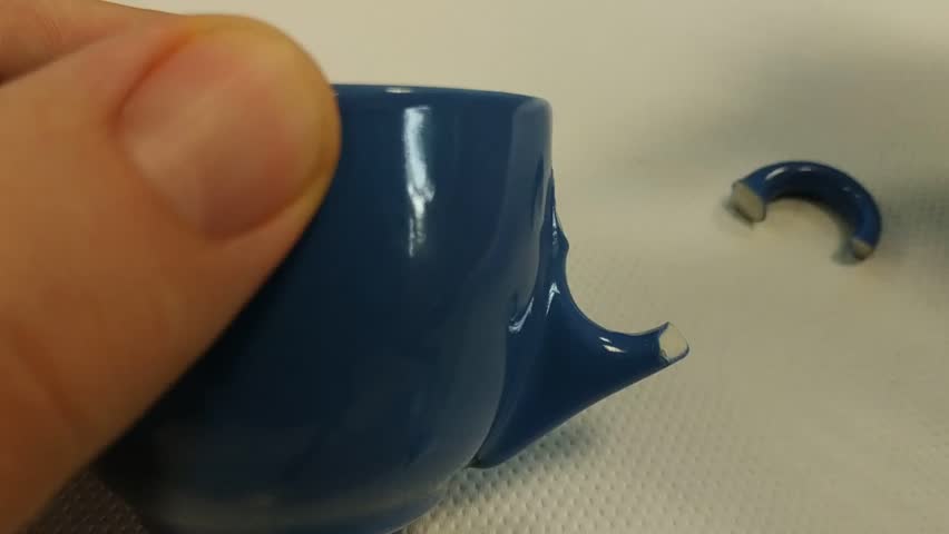 Repair a coffee cup with glue. The spout applies a drop of glue to the point, then the broken handle is placed and held in place while waiting for the glue to set. Royalty-Free Stock Footage #1020141985