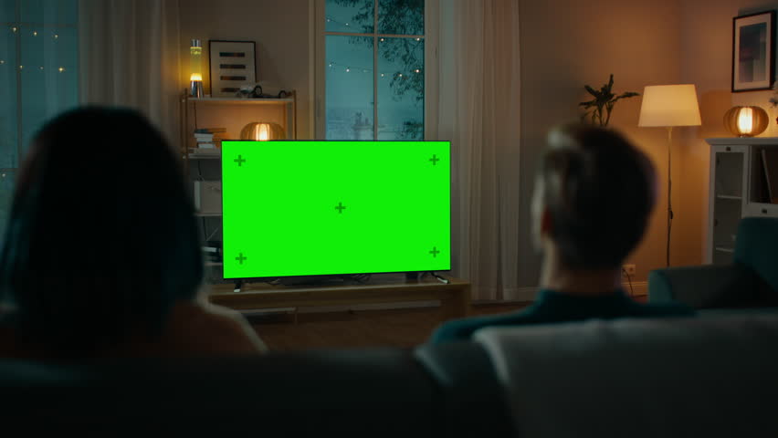 Couple Watches Green Mock-up Screen TV while Sitting on a Couch in the Living Room. Romantic Evening for Boyfriend and Girlfriend. Royalty-Free Stock Footage #1020144166