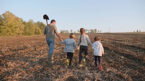Farmer with his four children going on the farm field for work together. Farmer with his large family walking on the field, steadicam shot, rear view.