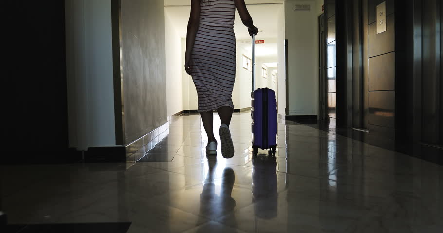 A young woman with a suitcase on wheels climbs the stairs and walks down the hall to a hotel room. The girl in a dress and sneakers came to rest. Room 534. | Shutterstock HD Video #1020156154