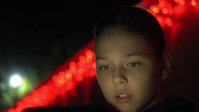 closeup of cute schoolboy with smartphone at night, fair red lights bg, 4k 