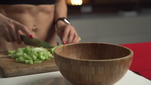 Sporty woman cuts celery on a cutting Board for cooking homemade vegetable salad.