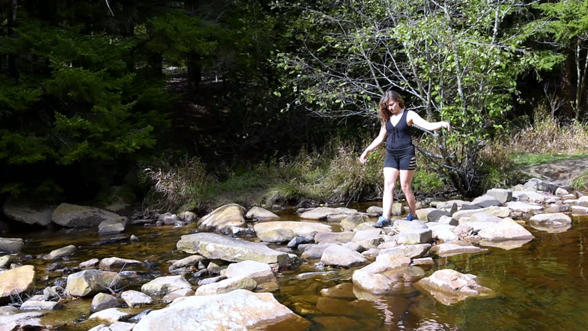 Young woman crossing Red Creek river near Dolly Sods, West Virginia when hiking with many stones, rocks, stepping, treading carefully