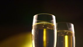 Champagne. Two Flutes with Sparkling Wine over golden Holiday Bokeh Blinking Background. Pouring champagne. Celebration. Party. Slow motion 4K UHD video 3840x2160