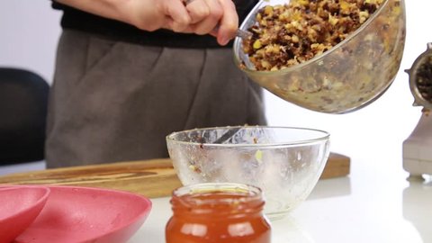 Woman adding honey to a nut butter and mixing ingredients in bowl